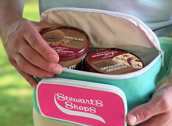 Person holding an open Stewart's Shops fanny pack containing two pints of Stewart's ice cream, showing its insulated interior.