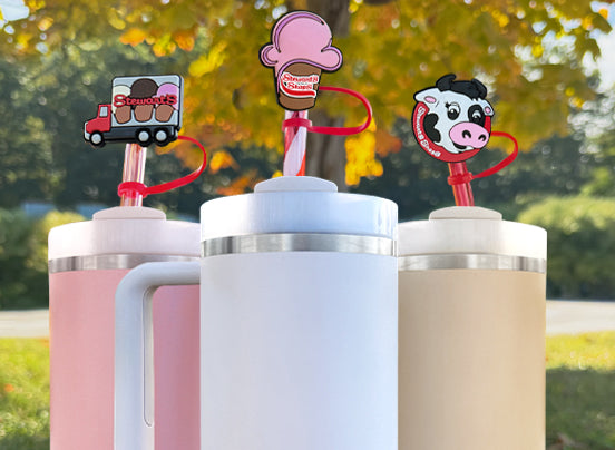 Three colorful tumblers with cartoon character straws against a blurred outdoor background
