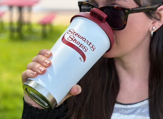Person holding a Stewart's Shops branded tumbler outdoors