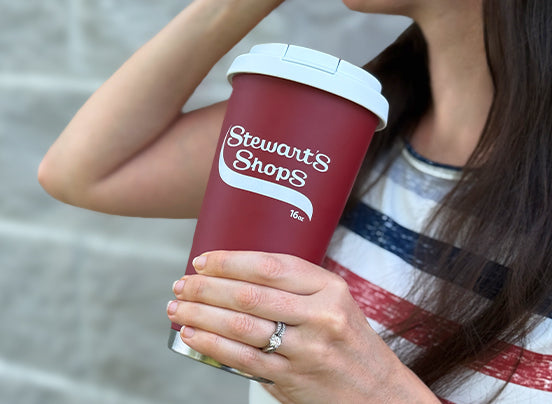 Person holding a red Stewart's Shops cup with a blurred background