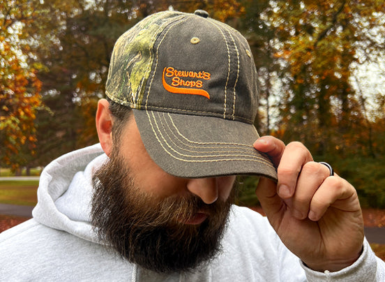 Man wearing Hat with Realtree Camouflage and an orange Stewarts Shops logo