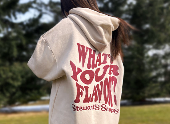 Oversized what's your flavor hoodie from the back in a park with trees.