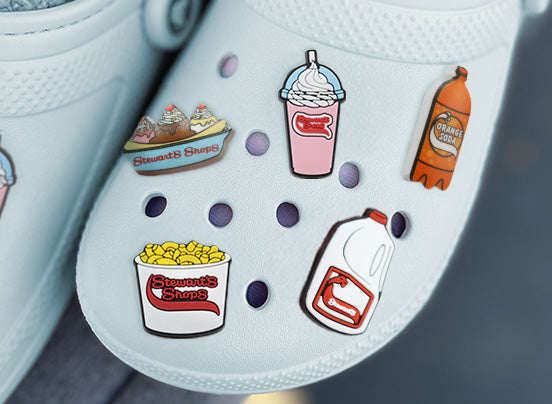 White shoe with colorful pins featuring food items and a bottle.