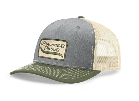 Angled view of a Stewart's Shops trucker hat featuring a heather gray front, olive green curved bill, cream mesh back, and an embroidered Stewart's Shops logo patch on the front panel.