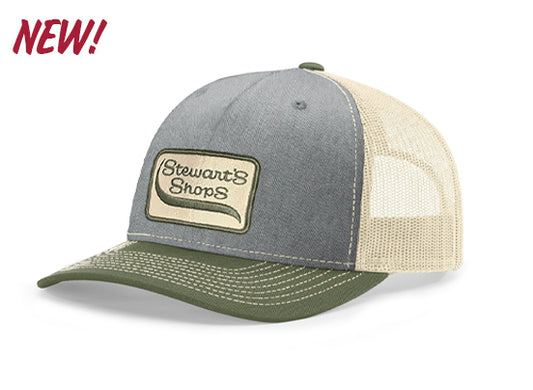 New Stewart's Shops gray and olive green trucker hat featuring a stitched Stewart's Shops logo patch on the front, an olive green curved bill, and a cream mesh back. Available online and in select Stewart's Shops locations.