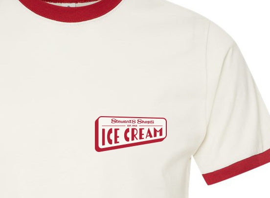 Close-up of a vintage white ringer T-shirt with red trim on the collar and sleeve cuff. The chest features a red “Stewart’s Shops Ice Cream” logo graphic printed on the front.
