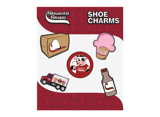 Image of a set of Stewart's Shops-themed shoe charms on a red background. The charms include designs of a milk carton, a pink ice cream cone with the Stewart's Shops logo, a red circular charm with a cow illustration, a Stewart's Shops delivery truck, and a chocolate milk bottle. 
