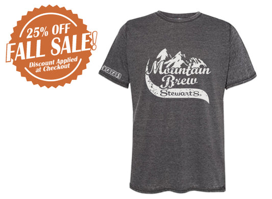Dark gray short-sleeve t-shirt with white graphic featuring stylized mountain peaks and the text “Mountain Brew Stewart’s” across the front. The left sleeve has small white lettering that reads “Stewart’s.” To the left of the shirt is an orange badge-shaped graphic with white text that says “25% OFF FALL SALE! Discount Applied at Checkout.”